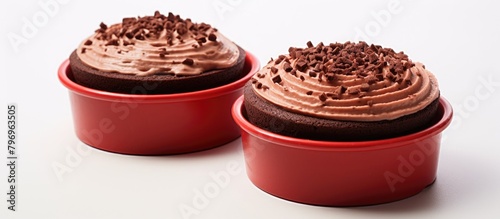 Two crimson cups topped with chocolate frosting