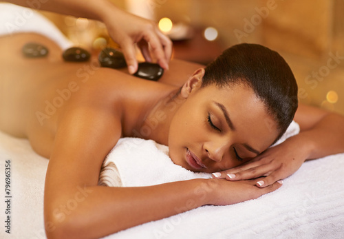 Spa, stone and woman with massage, wellness and relaxing with stress relief, skincare and vacation. Person, resort and girl with health, treatment and calm with zen therapy masseuse and body luxury