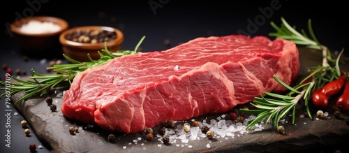 Piece of steak on cutting board with assorted spices and pepper