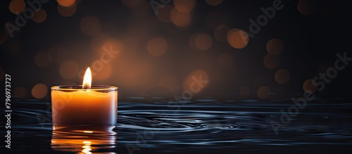 A flickering candle on water with a dark backdrop