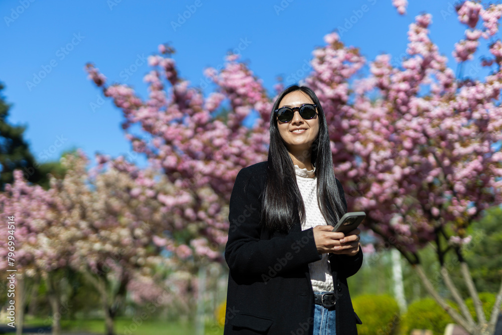 In a Japanese springtime garden, a happy woman enjoys the blooming sakura, radiating joy and beauty. In a Japanese springtime garden, a happy woman enjoys the blooming sakura, radiating joy and beauty.