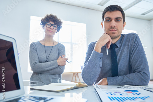 Portrait of two colleagues man and woman working with charts and graphs at office table