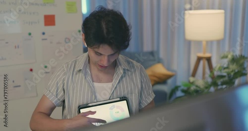 A young employee engagingly presents statistical data on a tablet in a comfortable and modern home office setting.