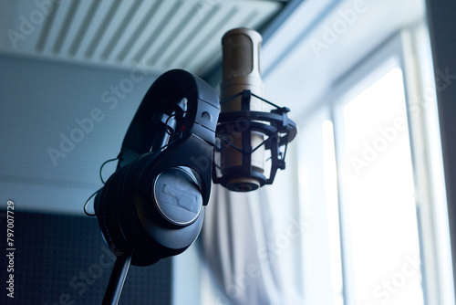 Professional condenser studio microphone and headphones hanging on stand photo