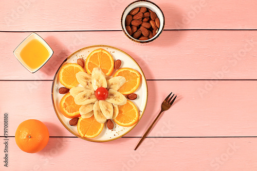 Healthy breakfast with ingredients, fun food for kids, food decoration ideas, healthy and natural food concept. Flower of bananas, oranges and nuts on a plate,