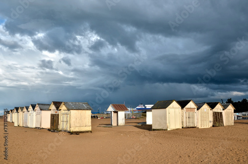 Beach cabins on the beach at Ouistreham with a very dark sky. in the Calvados department in the Basse-Normandie region in northwestern France.