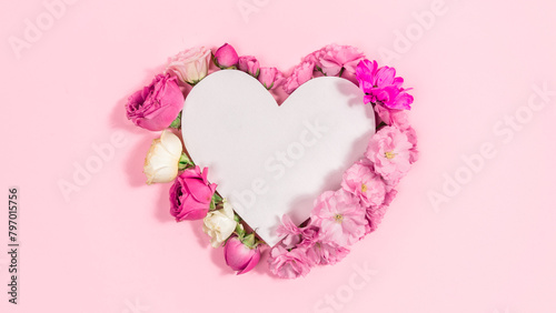 Natural roses and sakura flowers near white paper heart.