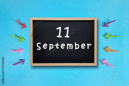 September 11 written in chalk on black board. Calendar date 11th of September on chalkboard on blue blurred school stationery background. Back to school. School event schedule date. Month of autumn. photo