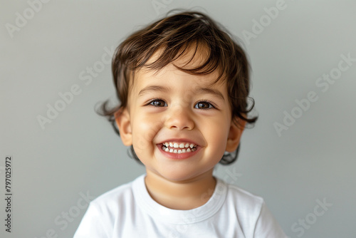 A smiling baby with a white shirt and brown hair