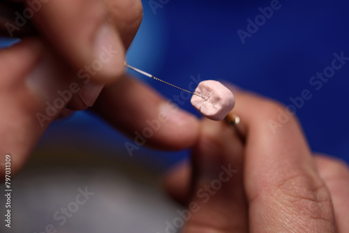 Dental prosthetics work. Dental technician working with dentures in a prosthetics laboratory. A technician uses a ceramic carving tool to make fissures on the crown of a dental implant.