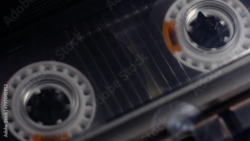A tape recorder is playing an audio cassette. Close-up. A vintage audio cassette spins on a blank label tape used to record sound in a retro cassette player. Recording of conversations.