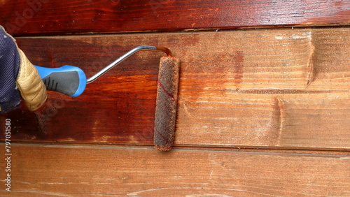 Rinnovare e verniciare la parete di legno vecchio con impregnante. Applicazione del colore con il rullo. photo