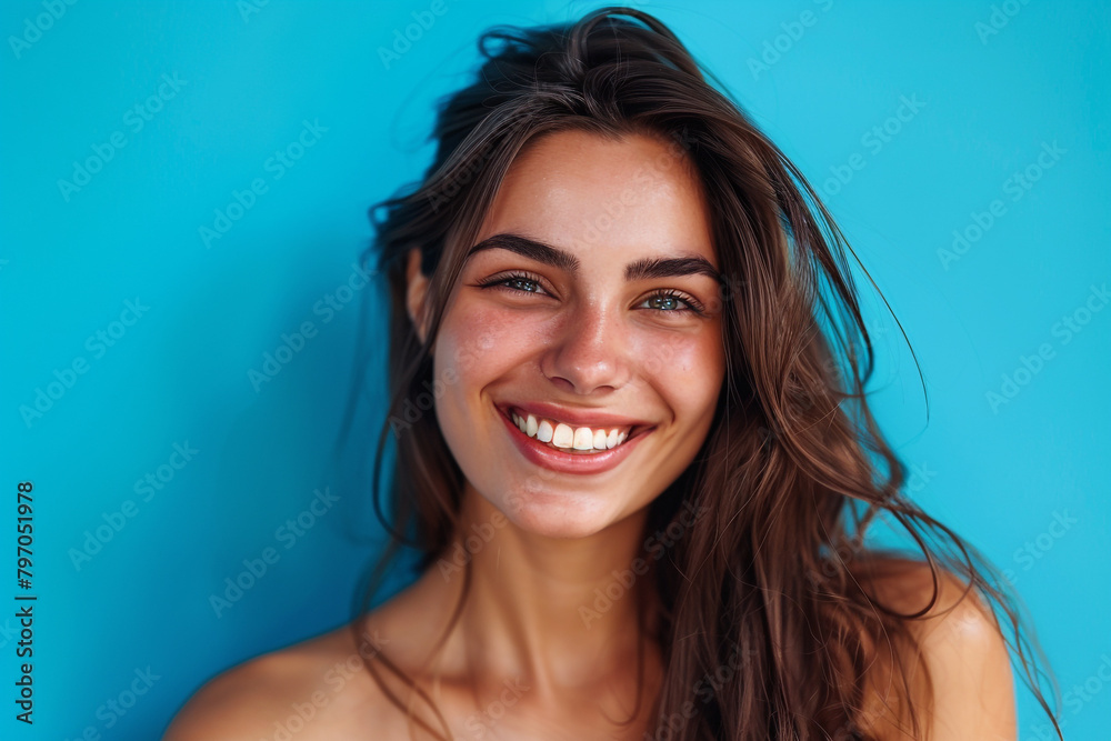 Smiling beauty against vivid blue backdrop, showcasing empty space for ad Smiling beauty against vivid blue backdrop, showcasing empty space for ad