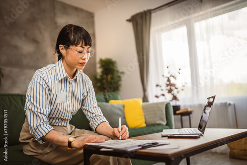 Mature japanese woman with eyeglasses work from home and sign document