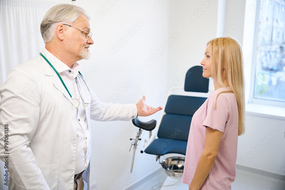 Senior man doctor in white medical uniform welcome woman patient Senior man doctor in white medical uniform welcome woman patient