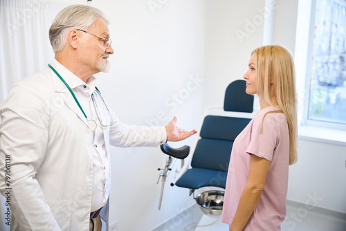 Senior man doctor in white medical uniform welcome woman patient