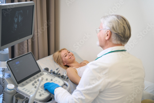 Doctor using ultrasound scan examining smiling woman