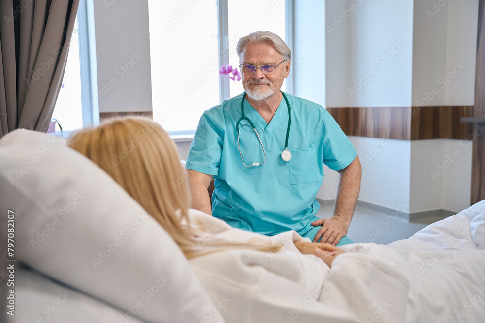 Fototapeta premium Friendly male therapist talking to beautiful female patient