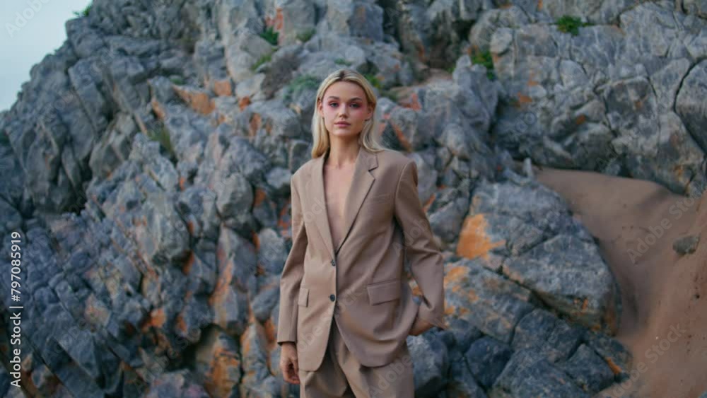 Fashion model shooting beach in elegant suit. Sexy blonde look camera at shore Fashion model shooting beach in elegant suit. Sexy blonde look camera at shore