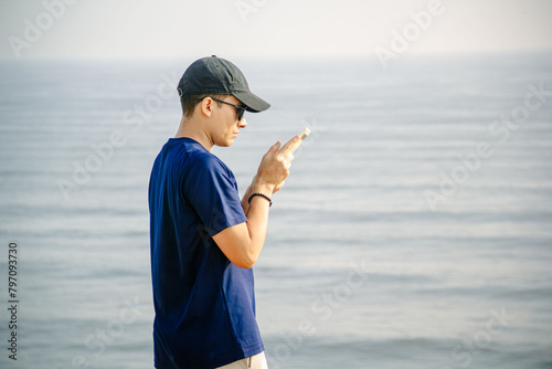Engrossed in the digital world, he finds solace amidst the vast expanse of the beach. With legs perched atop a sand dune, he navigates the endless possibilities on his phone © Isaac