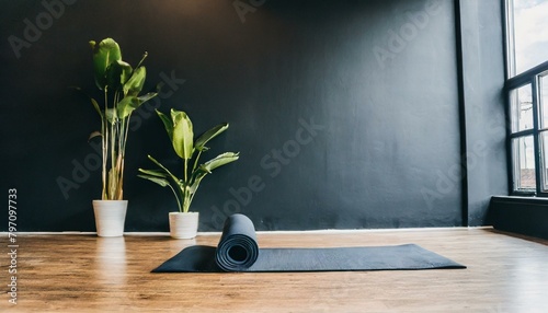 an elegant gym studio with a yoga mat set amidst calming props framed by a large black wall for textual content photo