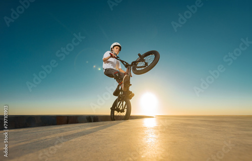 A teenager BMX Racing Rider performs tricks in a skate park on a pump track.