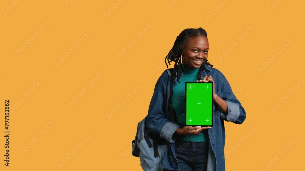 Smiling african american woman presenting tablet with green screen display, isolated over studio background. Cheerful BIPOC person creating promotion with chroma key device, camera B Smiling african american woman presenting tablet with green screen display, isolated over studio background. Cheerful BIPOC person creating promotion with chroma key device, camera B