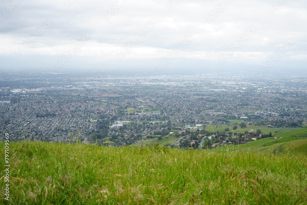 Obraz premium Gaze upon the bustling cityscape of San Jose from atop a verdant hill—a breathtaking vista that merges urban sophistication with the tranquil beauty of nature.