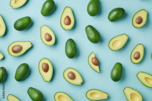 Pattern of colorful and fresh avocados both whole and cut in half spread neatly on a bright blue backdrop.