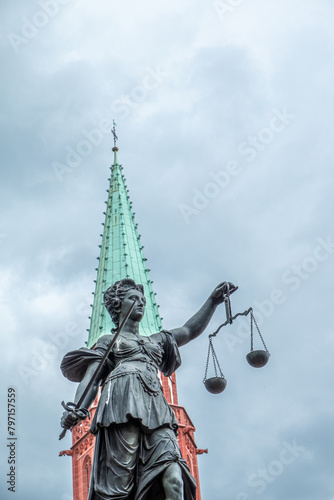 statue of lady justice under cloudy sky with church tower
