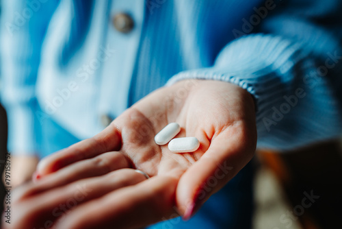 Close up of woman's hand holding two pills	
