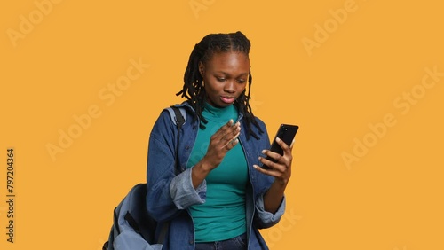 Upset african american woman arguing with friends during teleconference meeting on smartphone, studio background. Annoyed girl fighting on mobile phone videocall with mates, camera A photo