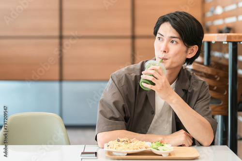 カフェでランチを食べながらグリーンスムージーを飲む若い男性（酵素・ヘルシー・食物繊維・健康食品）  © buritora