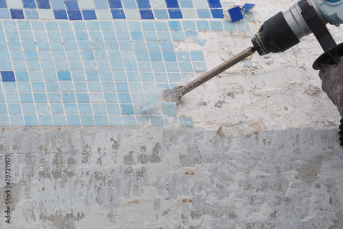 Removing old tile in swimming pool. Pool repairing work. Close-up.