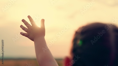 Hand happy baby at sunset. Silhouette hand of kid close-up in sun. Child stretches hand to sun. Silhouette palm pull to sun. Religion lends help hand. Prayer in religion. Concept faith religion prayer