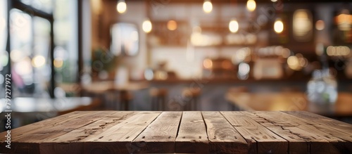 A close-up view of a wooden table inside a restaurant, set against a blurry background creating a warm and cozy atmosphere photo