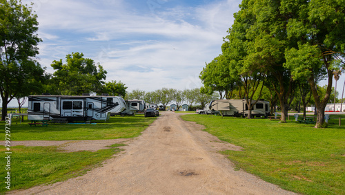 Large Rv trailers parked at campsite on trees under cloudy sky