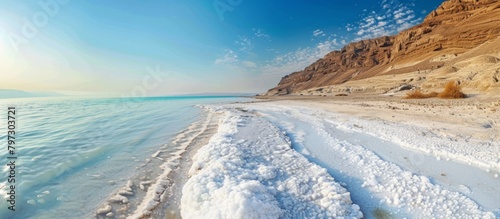 Scenic winter landscape showing a beach covered in snow with scattered rocks lining the shore