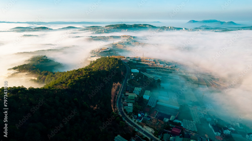 Naklejka premium An aerial view of a city in the morning. The city is surrounded by clouds.
