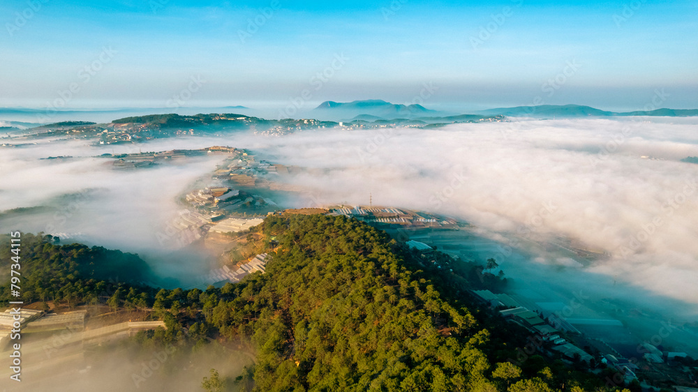 An aerial view of a city peeking through a thick layer of fog in the morning.
