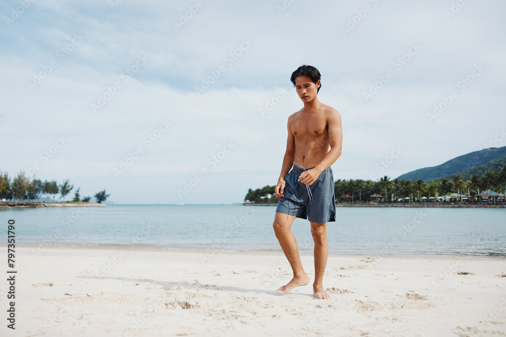 Fototapeta premium Muscular Asian Man Running on the Beach at Sunset, Exuding Strength and Energy in a Healthy Lifestyle Portrait