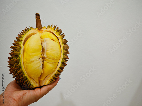 hand holding half peeled durian fruit on white background