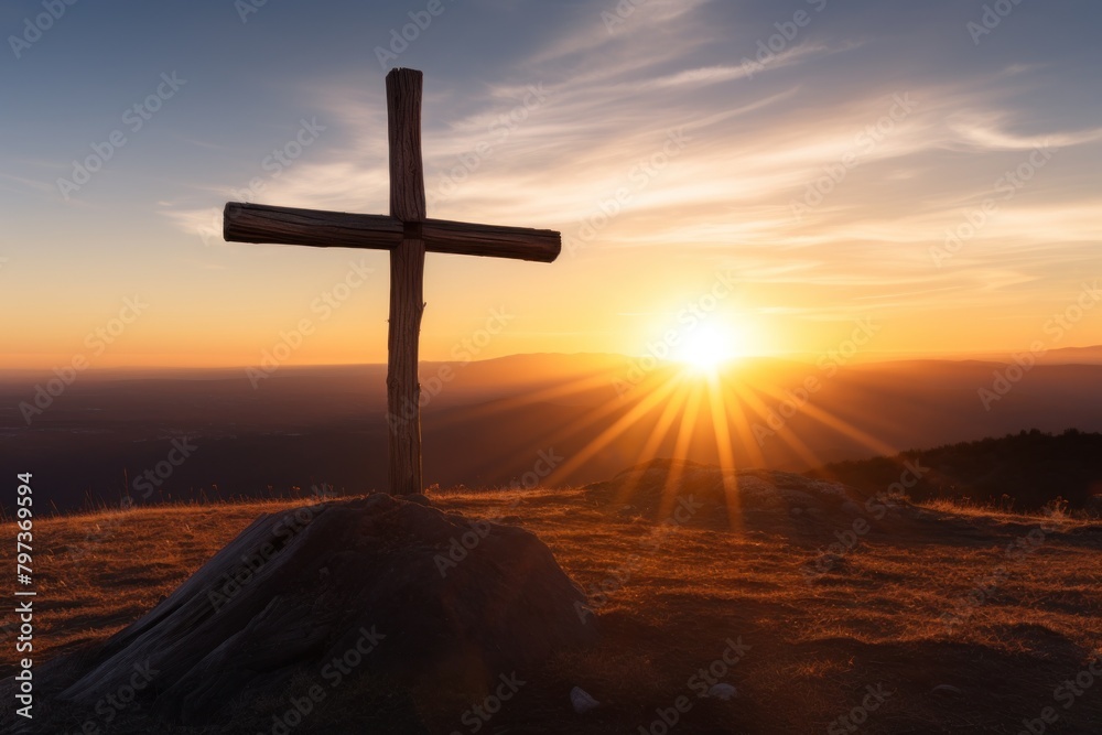 a cross on a hill with the sun shining through the clouds