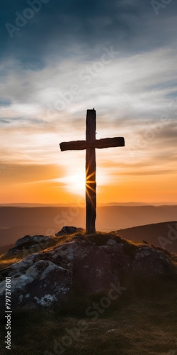a cross on a hill with the sun shining through