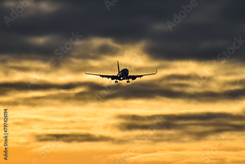 commercial airplane coming in for a landing at dusk, with dramatic sky in the background.
