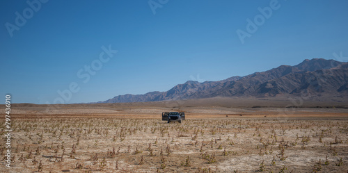 Safari, travel, extreme adventure or expedition in the desert. Desert with mountains on the horizon, dry grass and cracked earth. Off-road expedition.