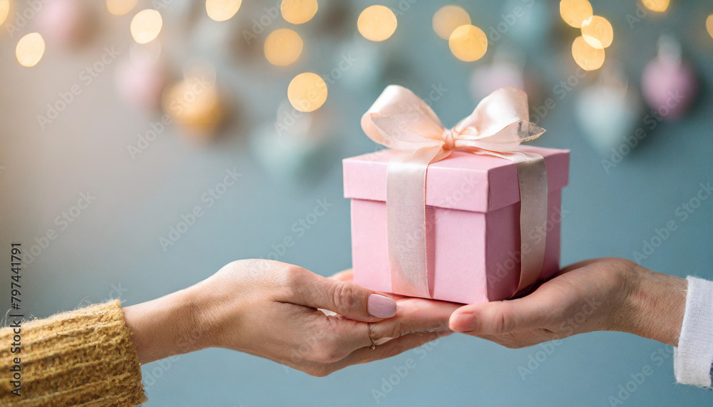 woman's hand offers bright pastel gift box to another woman's hand, symbolizing Mother's Day joy and appreciation woman's hand offers bright pastel gift box to another woman's hand, symbolizing Mother's Day joy and appreciation
