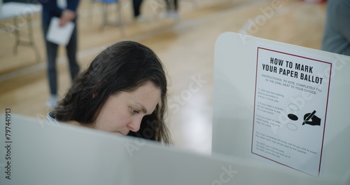 Female voter stands at voting booth. American citizens come to vote in polling station. Political races of US presidential candidates. National Election Day in the United States. Civic duty. Close up. photo