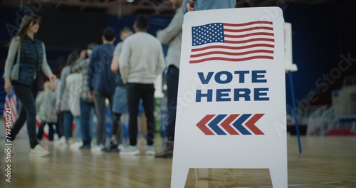 Vote here sign on the floor. Queue of multi ethnic American citizens come to vote in polling station. National Election Day in United States. Political races of US presidential candidates. Civic duty. photo