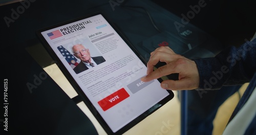 Close up of Caucasian man making choice and voting for US presidential candidate in voting booth using tablet computer. US citizen at polling station during National Election Day in the United States. photo